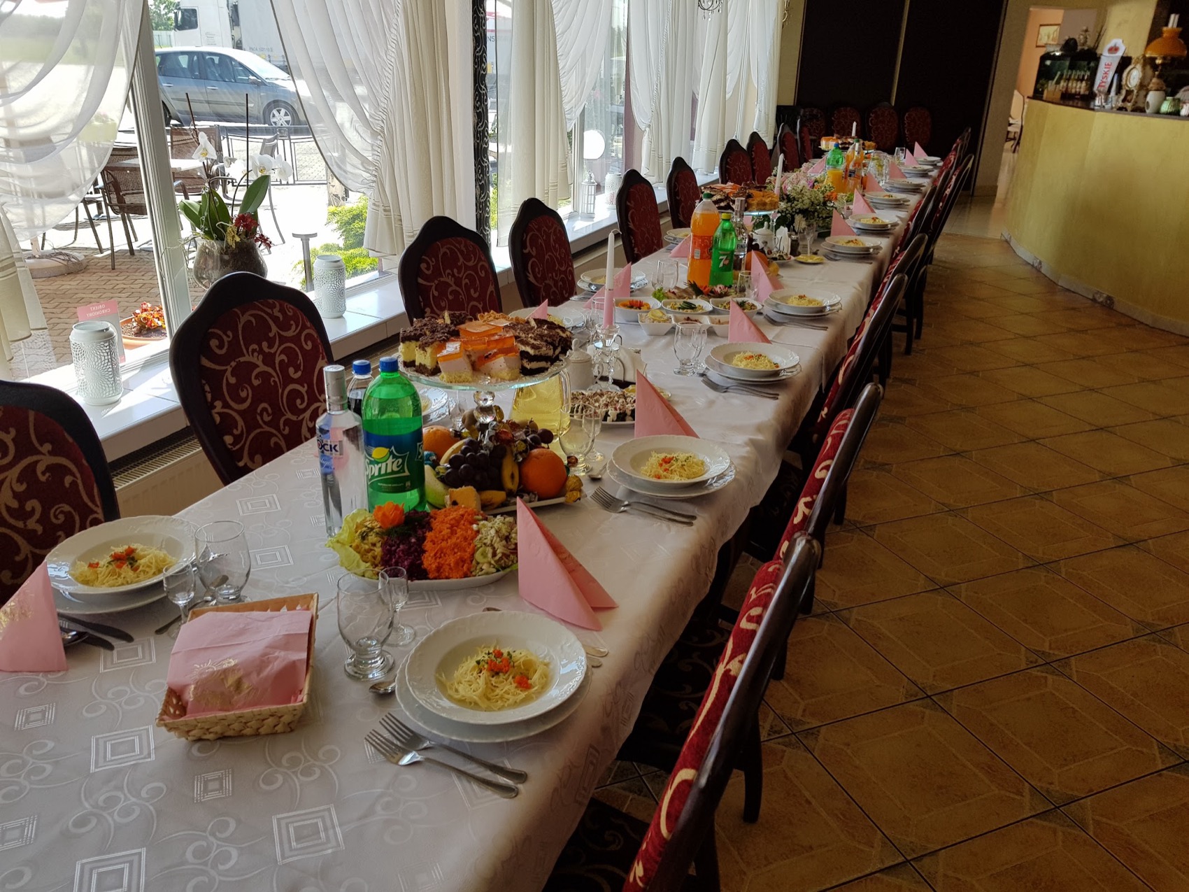 Długi stół przyjęciowy w MONIE, ciasto na paterze, owoce i przekąski dla gości