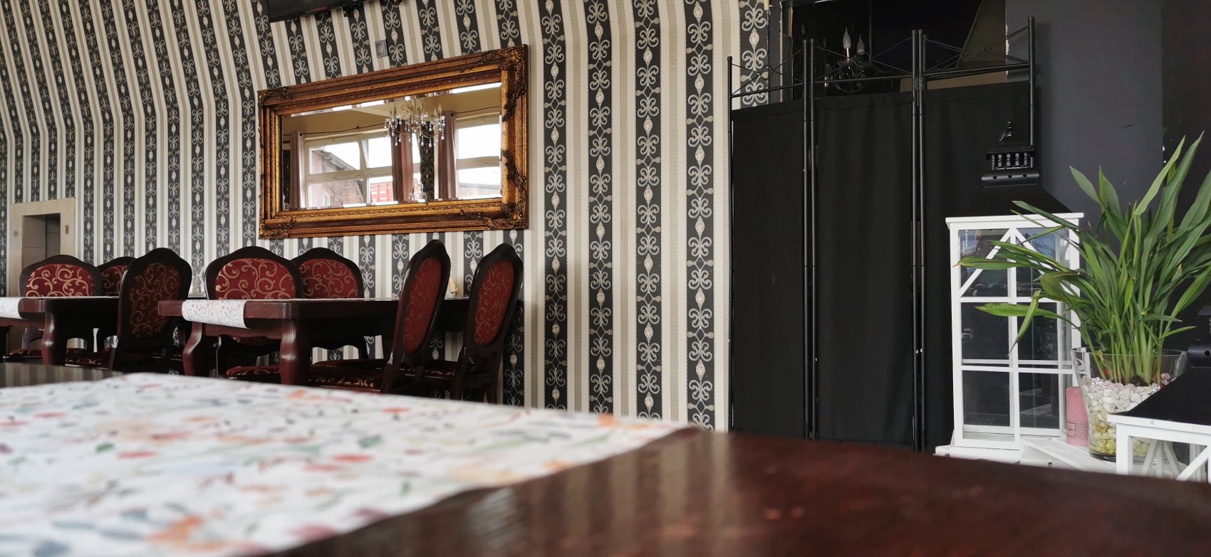 Złocone lustro i pasiasta tapeta w sali Restauracji MONA